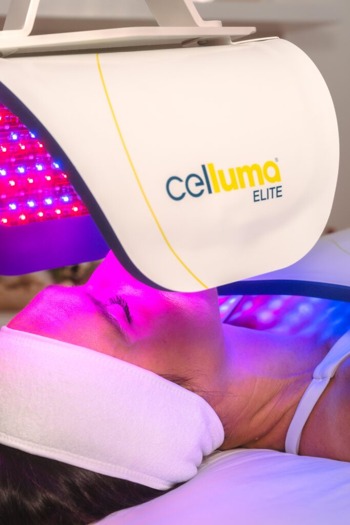 Patient receiving professional LED light therapy under a flexible Celluma-style panel in a modern aesthetics clinic.